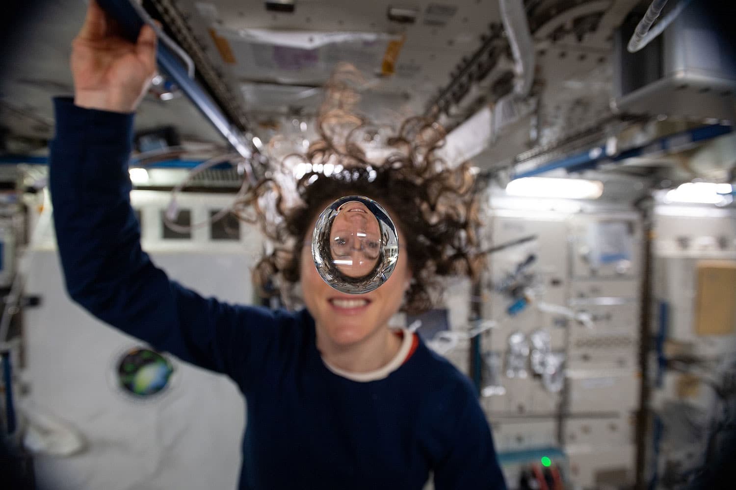 An astronaut aboard the International Space Station with a floating sphere of water